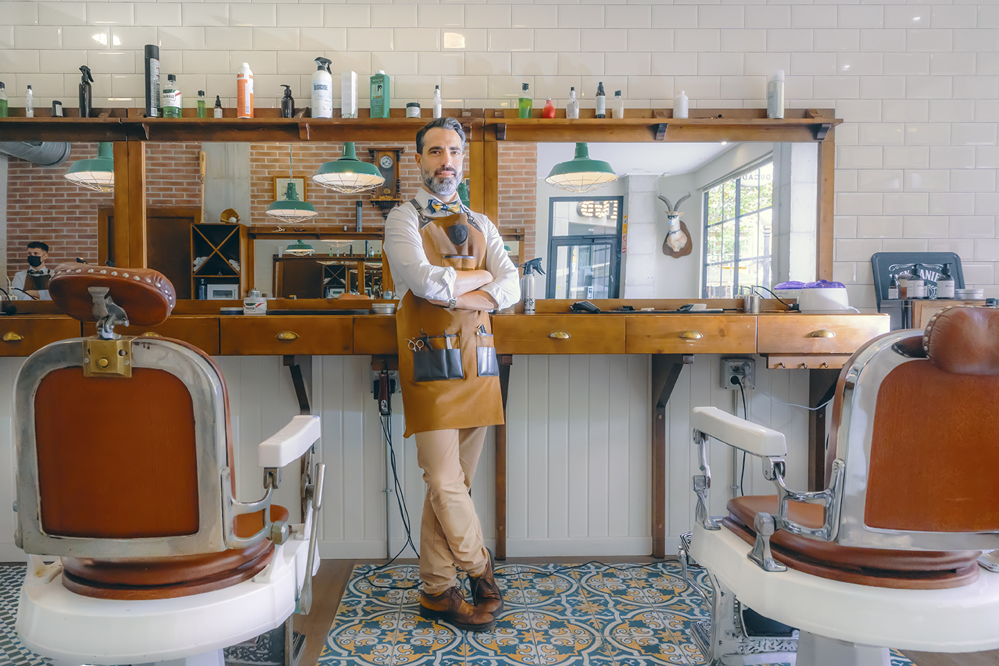 Imagen de un barbero posando a la cámara en su establecimiento. Lleva zapatos
                Pikolinos.